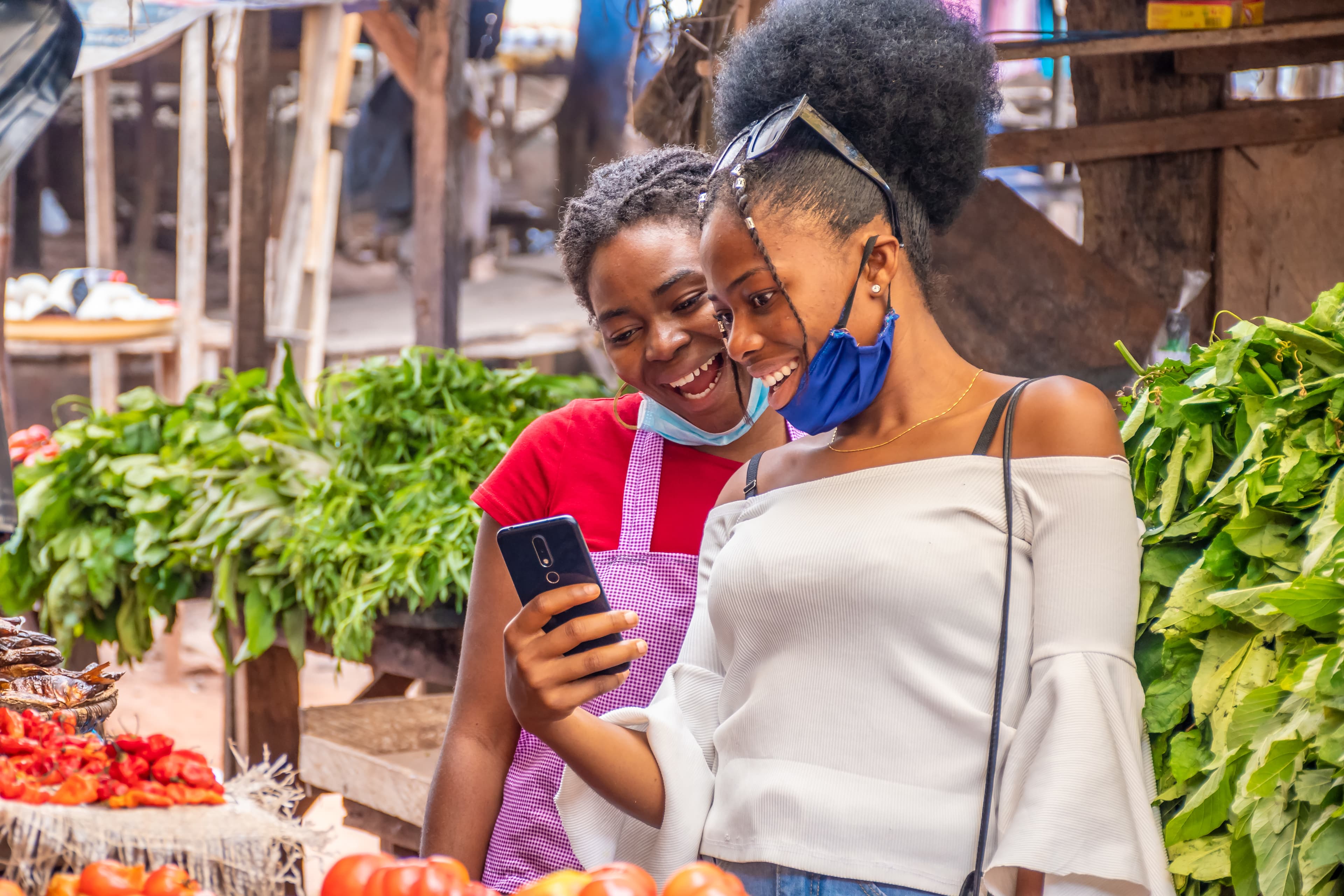 Commerçantes africaines utilisant DODJI sur leur téléphone au marché